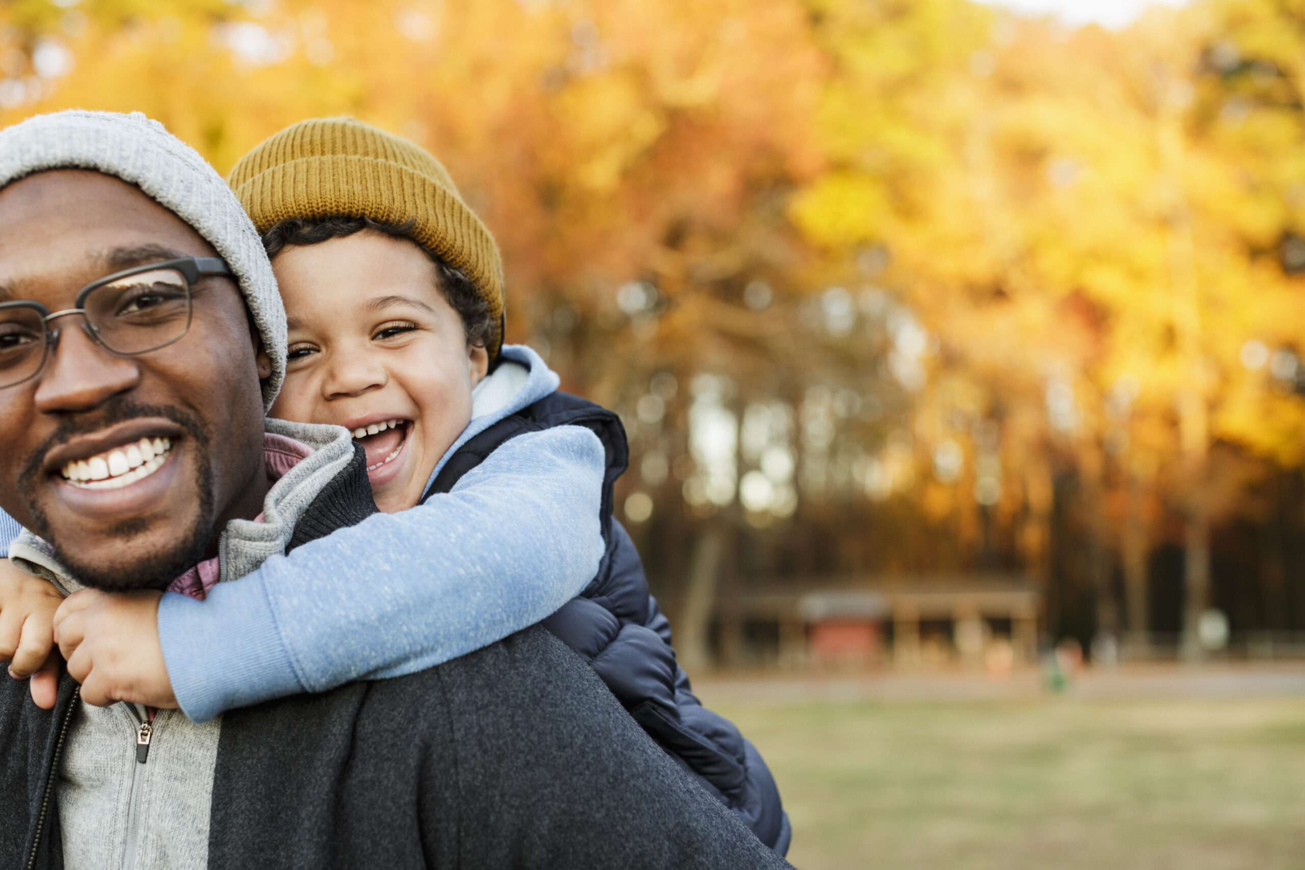 Adult and young child playing outside, smiling.
